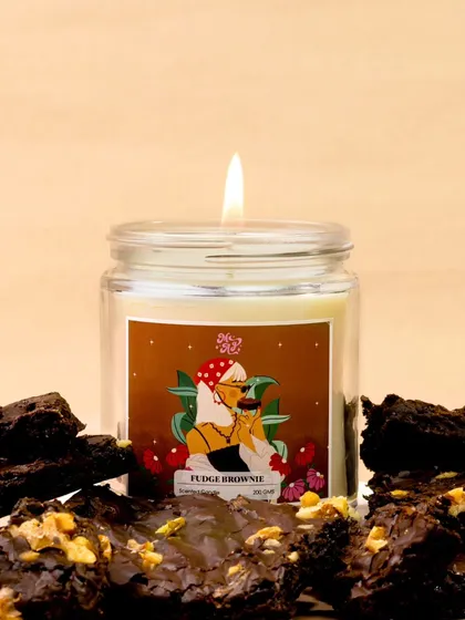 The rich, decadent scent of a fudge brownie candle is visualized by surrounding it with actual fudge brownies. This direct and delicious approach makes the fragrance almost tangible.