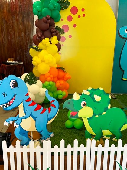 Another detail shot of the dinosaur-themed decor, showing the variety of friendly dinosaur characters. The balloon garland incorporates earthy tones to enhance the jurassic theme.