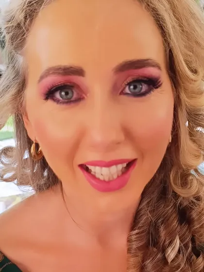 A happy client ready to party! Her smile says it all. The curly hair and bright makeup create a fun and festive vibe.