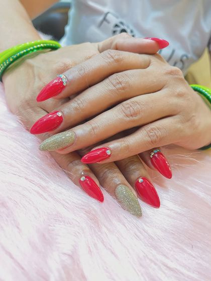 A vibrant and celebratory nail set. We combined bright red stiletto nails with gold glitter accent nails and finished with a few carefully placed rhinestones for extra sparkle.