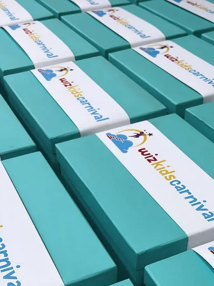 Bright and cheerful custom hampers for Wizkids Carnival. The vibrant turquoise boxes with branded sleeves show how we can match our packaging to your event's theme and energy.
