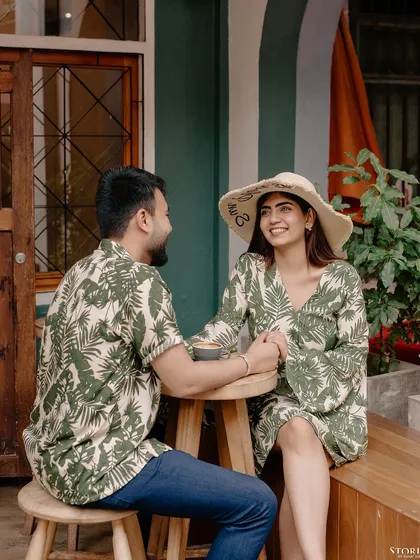 A charming cafe scene in Thailand, with the couple sharing a moment over coffee, dressed in matching tropical prints.