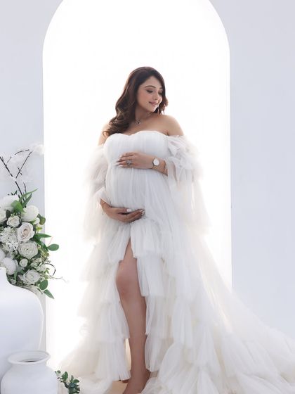 An angelic vision in white. The layers of tulle on this gown create a soft, dreamy effect as the mom-to-be stands in a beautifully lit archway.