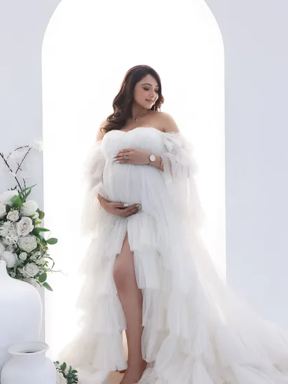An angelic vision in white. The layers of tulle on this gown create a soft, dreamy effect as the mom-to-be stands in a beautifully lit archway.