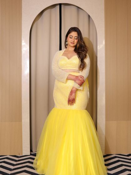 A stunning plus-size fish-cut lehenga in a vibrant yellow. Perfect for a Haldi or Sangeet, this outfit is designed to turn heads and is available to rent.