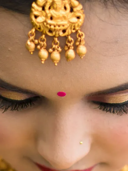 A close-up of my signature eye makeup. This look features a warm, golden shimmer on the lids, precise eyeliner, and full lashes to make the eyes pop, finished with a traditional bindi.