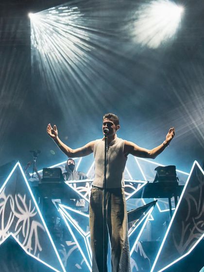 A performer sings live on stage with Alan Walker, showcasing the live vocal elements of the Walker World tour.