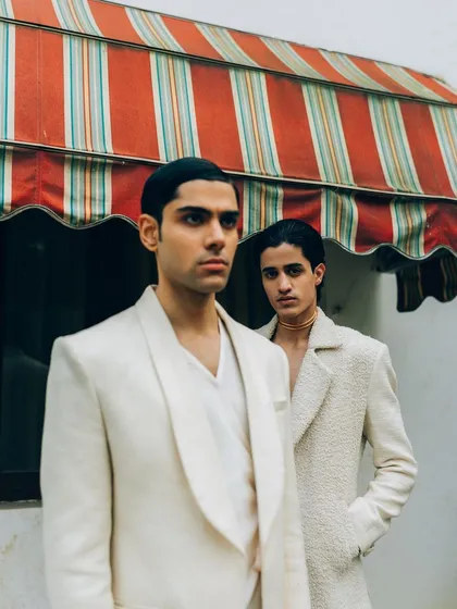 A menswear editorial for designer Sanchit Sharma. The composition uses architectural elements and clean lines to frame the subjects, creating a sophisticated and modern look.