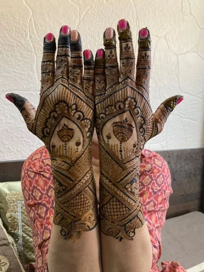 A happy client showing off her bridal mehandi. The design features a unique pattern with hanging motifs in the center of the palm.