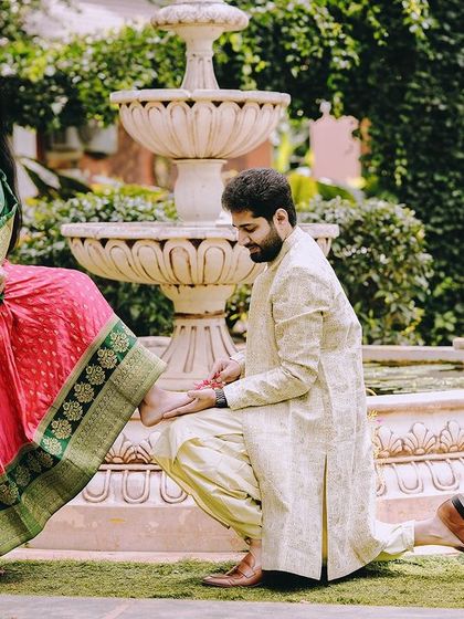 A chivalrous and traditional pose, with the groom kneeling at the bride's feet by a fountain, a nod to classic romance.