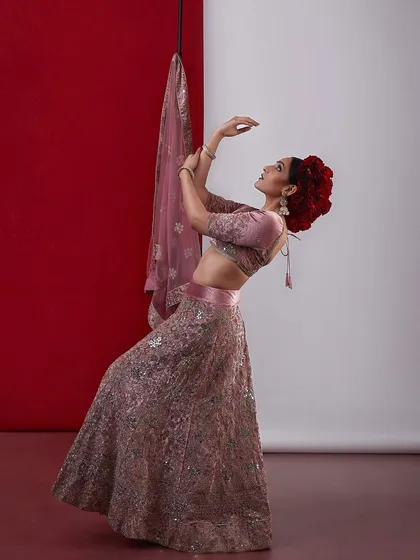 An elegant and graceful bridal look in a pink lehenga, with a beautiful floral bun and delicate makeup.