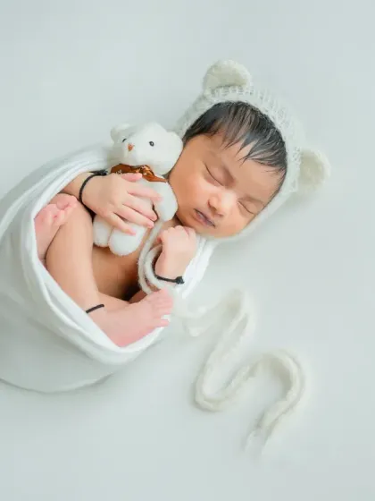This full-body shot shows the classic 'potato sack' wrap, which keeps the baby snug and secure while showing off their tiny feet.