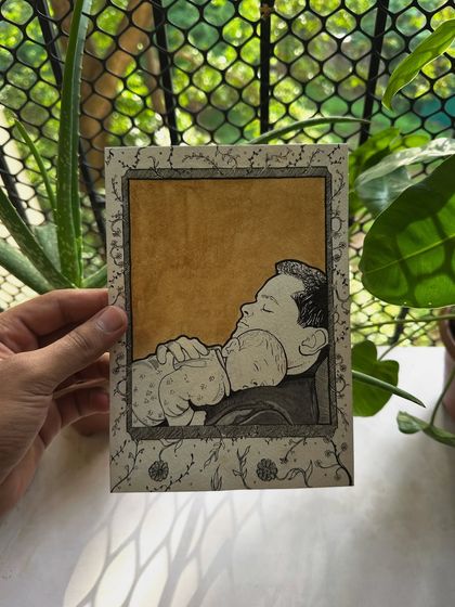 The custom father and baby illustration held against a natural background. The greenery really complements the earthy tones of the coffee paint.