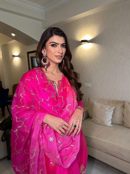 The full look, showing how the soft glam makeup pairs beautifully with the bright pink traditional outfit and statement earrings.