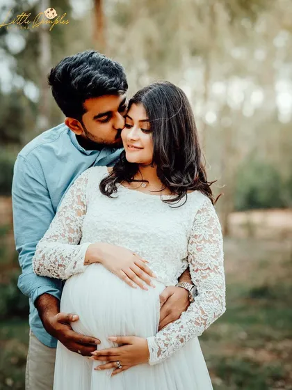 A sweet kiss on the cheek during a golden hour outdoor maternity shoot. The delicate lace dress and soft light create a romantic and gentle feel.