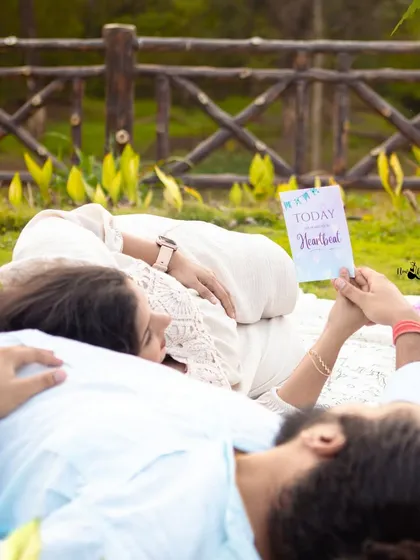 A creative and intimate shot of the couple lying on the picnic blanket. It focuses on their connection and the little book they are sharing, a sweet detail of their story.