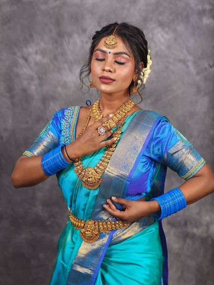 This studio portrait captures a moment of quiet contemplation, with the rich blue of the saree providing a beautiful splash of color.