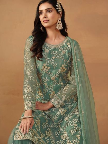 This teal-green net suit is so refreshing. The intricate sequence work and sharara style make it a trendy yet traditional choice for your next event.