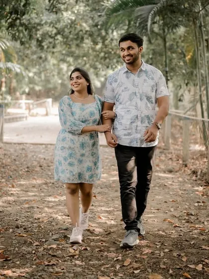 A lovely shot of the couple taking a walk through a park. This classic, candid-style photo captures a simple moment of togetherness in a beautiful, sunlit setting.