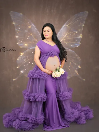 A magical studio portrait with edited-in fairy wings and a bare bump, showcasing the beauty of pregnancy.