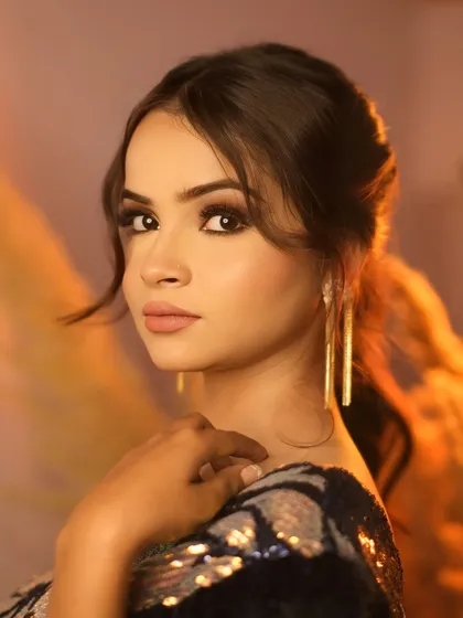 A close-up portrait of a model bathed in a warm, golden light, highlighting her glamorous makeup and elegant earrings. I love playing with light to create a mood, and this shot is all about that golden hour glow.