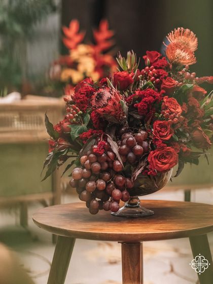 A centerpiece from the 'Orchard of Life' event, featuring grapes and red flowers in a vintage-style bowl.