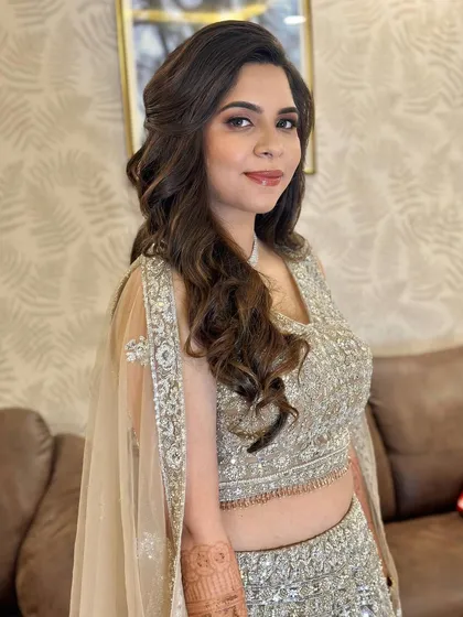 A side profile of the look, highlighting the soft waves in her hair and the radiant finish of her makeup.