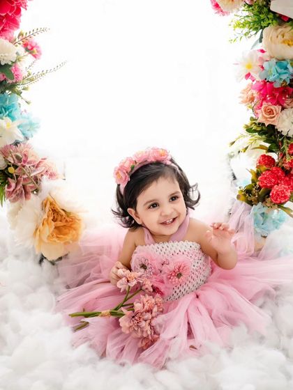 This little girl in her pink tutu looks like a real-life flower fairy, sitting among the clouds and a ring of blossoms.