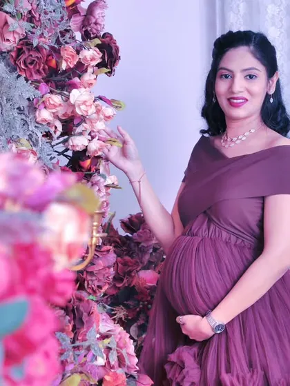 A lovely close-up shot focusing on the mother-to-be. The soft lighting and the detailed floral arrangements in the background create a gentle and intimate feel for this maternity photo.