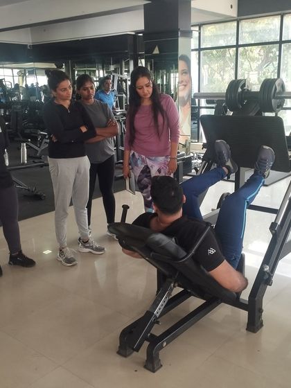 A trainer demonstrates the proper setup for a leg press, ensuring students can confidently guide their future clients.