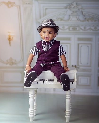 This little musician is ready for his close-up, sitting right on top of the piano with a stylish hat and a charming smile.