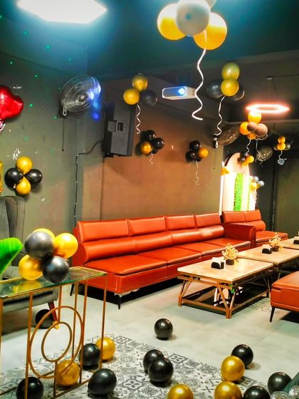 A stylish party setup in a private room with black and gold balloons. The decor is perfect for an adult's birthday or an anniversary celebration.