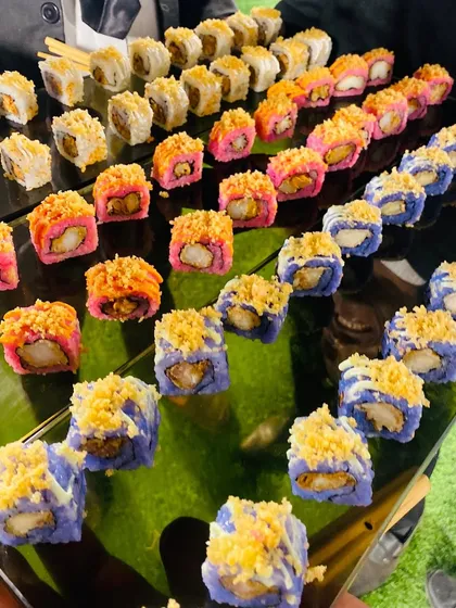 A vibrant platter of assorted sushi rolls, including prawn tempura rolls with pink and blue rice, showcasing my creative approach to presentation.