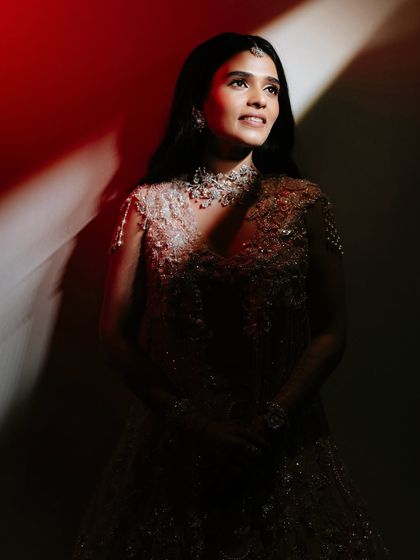 An artistic and moody shot that plays with light and shadow, highlighting the bride's beautiful features and the shimmering quality of her makeup.