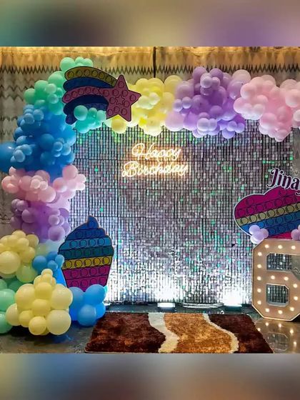 A vibrant Pop-It themed birthday party, using a rainbow of pastel balloons, a sequin backdrop, and custom Pop-It shaped props.