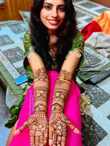 A smiling bride showing her full-arm portrait mehndi, ready for her wedding festivities.