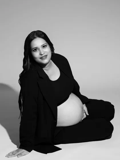 A modern black and white maternity portrait showcasing a relaxed and happy mom-to-be. Monochrome photography adds a timeless, soulful quality to pregnancy photos, focusing on emotion and form.