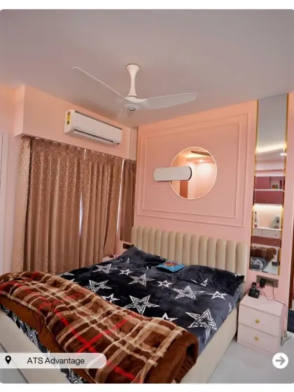 A bedroom with a soft pink color scheme and a modern fluted headboard. The round mirror and integrated shelving create a functional and chic vanity space.