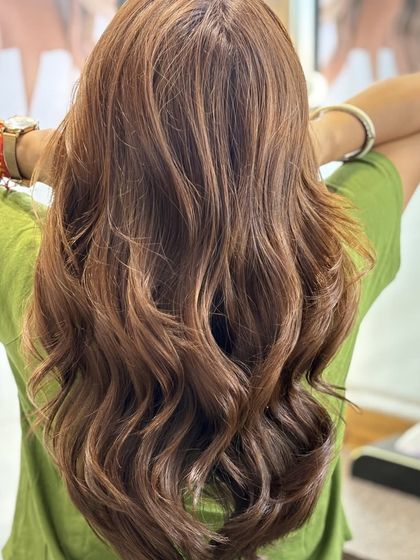 A warm, coppery brown hair color that glows. Styled in loose waves, this look is perfect for someone wanting a touch of warmth and vibrancy in their hair.