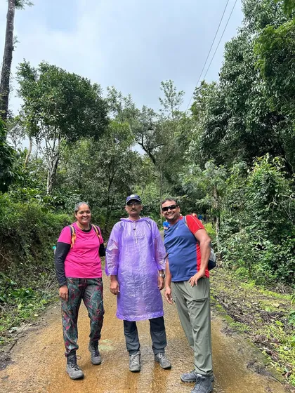A group of trekkers on a muddy path during the Thadiyandamol trek, equipped with raincoats for the unpredictable monsoon weather.