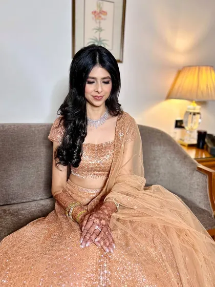 Another beautiful shot of the bride on the couch. The warm lighting enhances the golden tones of her lehenga and the radiance of her skin.