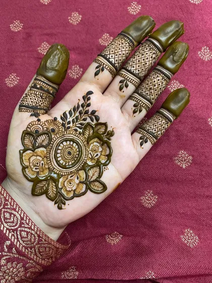 A beautiful floral bunch placed on the back of the hand, with detailed leaves and petals. The fingers are decorated with matching bands.