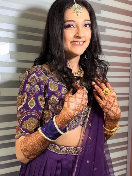A smiling portrait that captures the client's joy. The makeup is light and fresh, perfectly complementing her vibrant purple outfit.