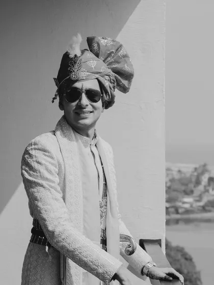 A classic black and white portrait of the groom on his wedding day. The traditional safa and textured sherwani create a look of timeless elegance, captured beautifully in this shot.