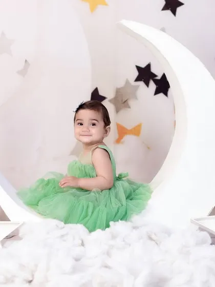 A sweet baby girl in a lovely green tulle dress, sitting on our moon and stars set. A magical and whimsical birthday portrait.