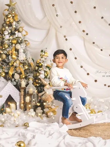 A little boy enjoying the magical Christmas setup, sitting on a white rocking horse.