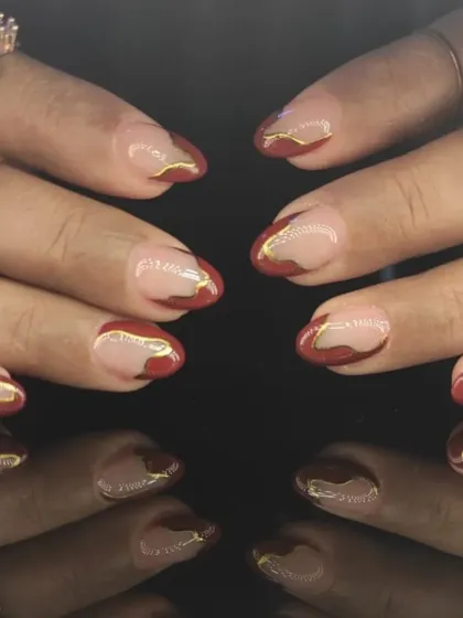 An abstract design using deep red polish over a nude base, creating a negative space effect that redefines the classic French tip.