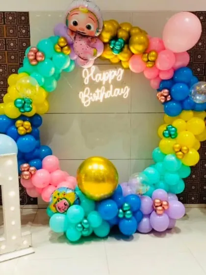A circular Cocomelon-themed backdrop perfect for photos. This setup features a full ring of colorful balloons, Cocomelon character cutouts, and a light-up number '1'.
