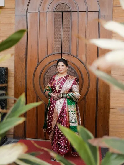 A full-length shot of our Maharashtrian bride in her maroon and green Paithani saree, showcasing the complete traditional look.
