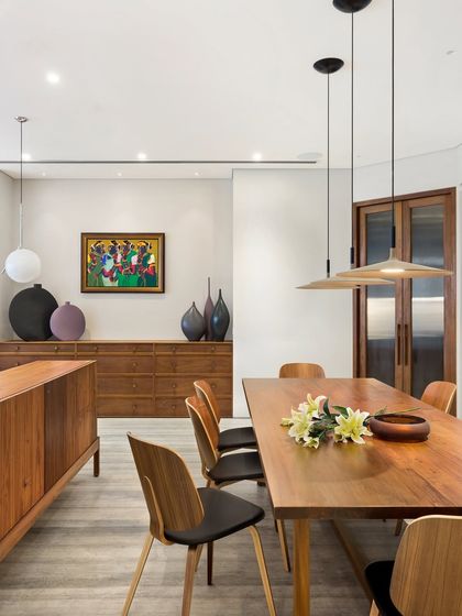 A different perspective of the Limestone Residence dining area, highlighting the elegant, modern chairs and the simple, clean lines of the wooden table and storage units.